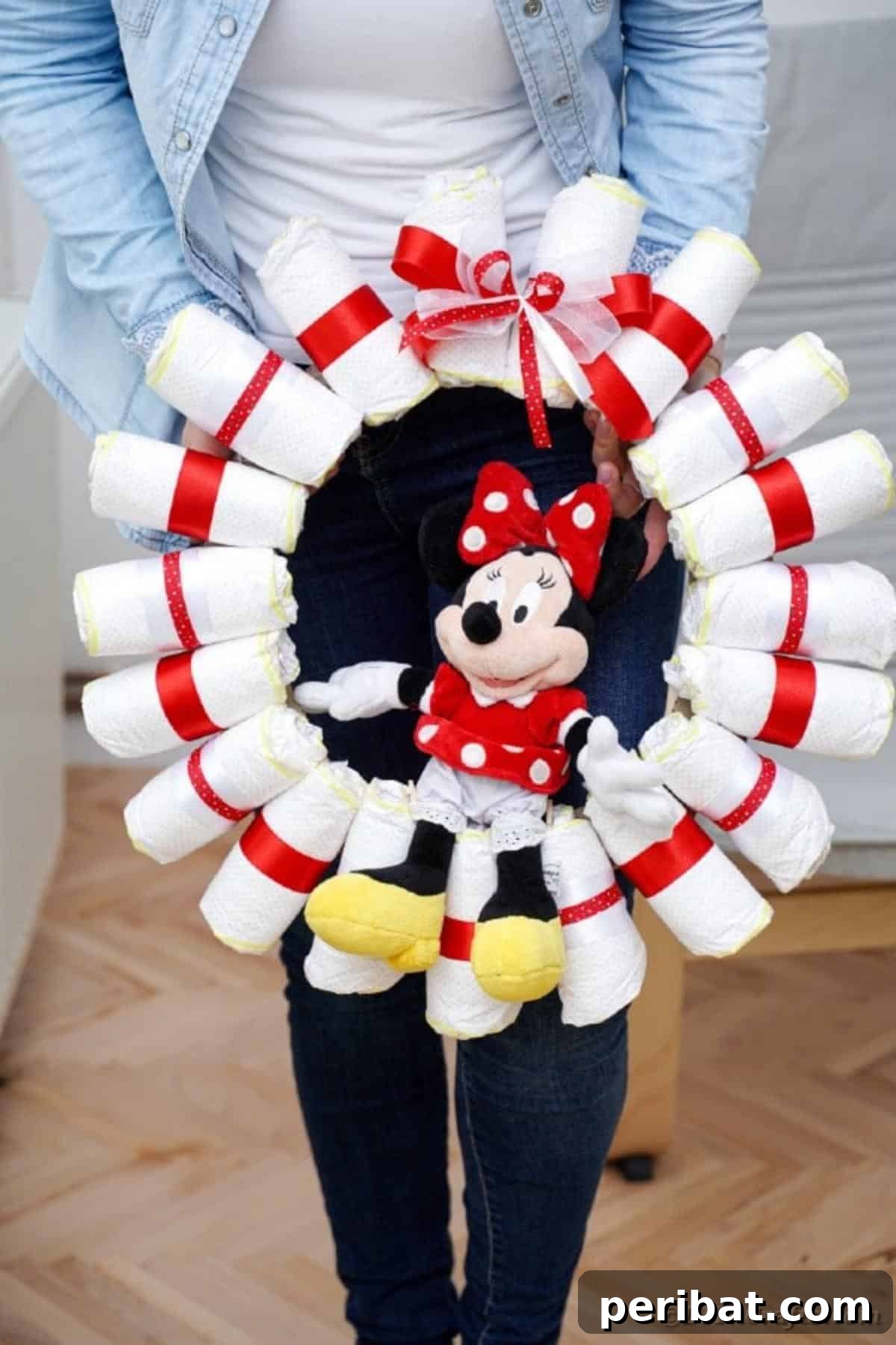 Woman proudly displaying a finished Minnie Mouse diaper wreath, showcasing its charm