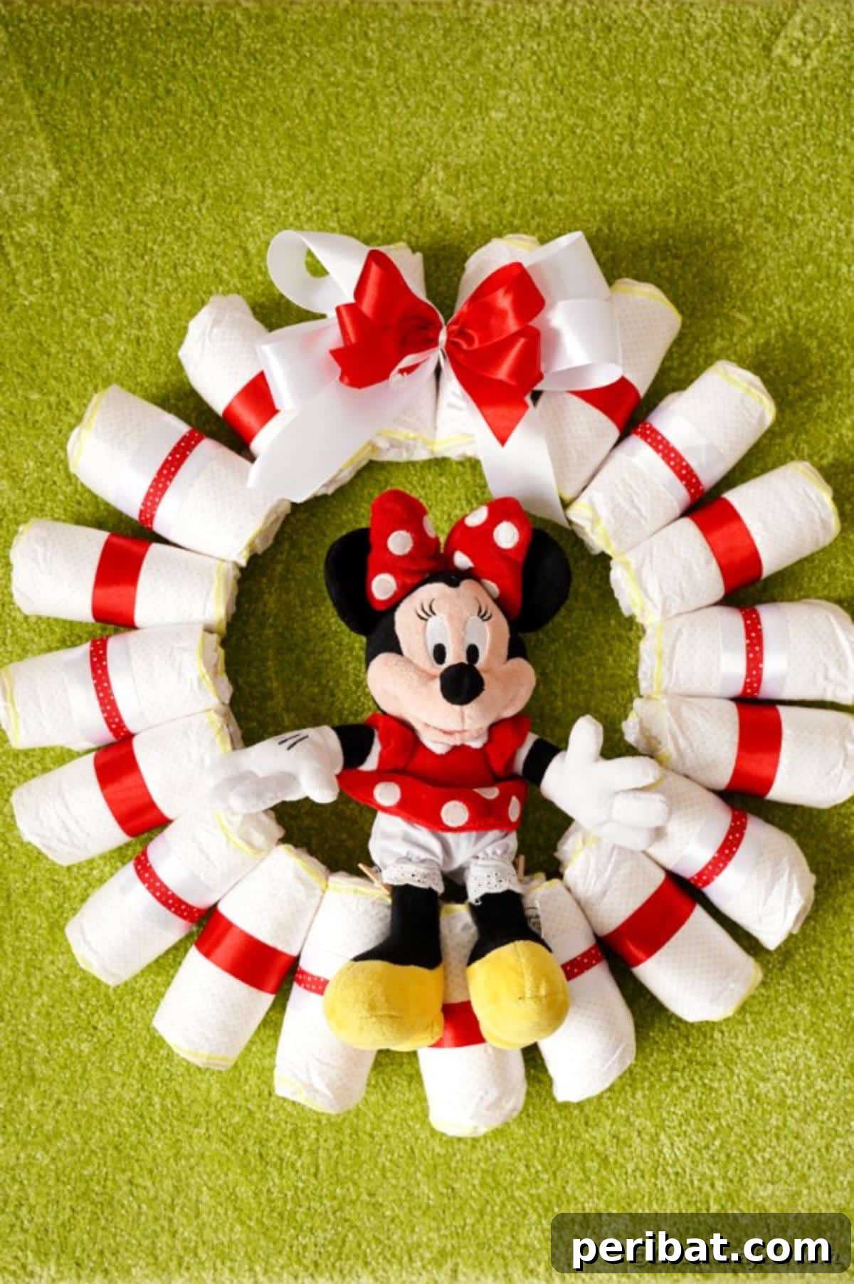 A completed diaper wreath resting on green grass, showcasing its handcrafted appeal