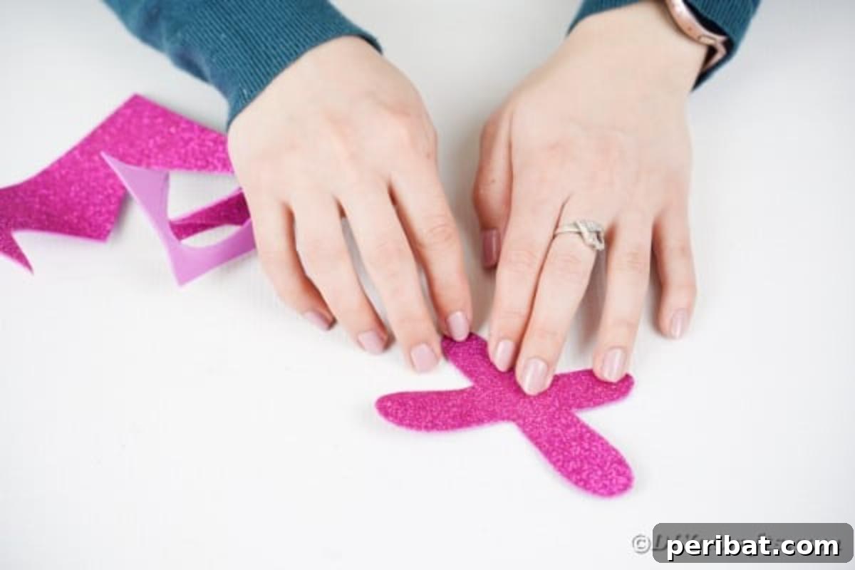 Create Vibrant Craft Stick Dragonflies for Kids 10 A pair of shimmering glitter foam wings laid flat, with a line of craft glue applied down the central fold, ready for attachment.