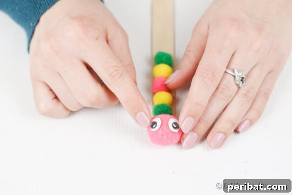 Create Vibrant Craft Stick Dragonflies for Kids 8 Placing two googly eyes onto the top pom-pom of a craft stick, which forms the head of the dragonfly craft.