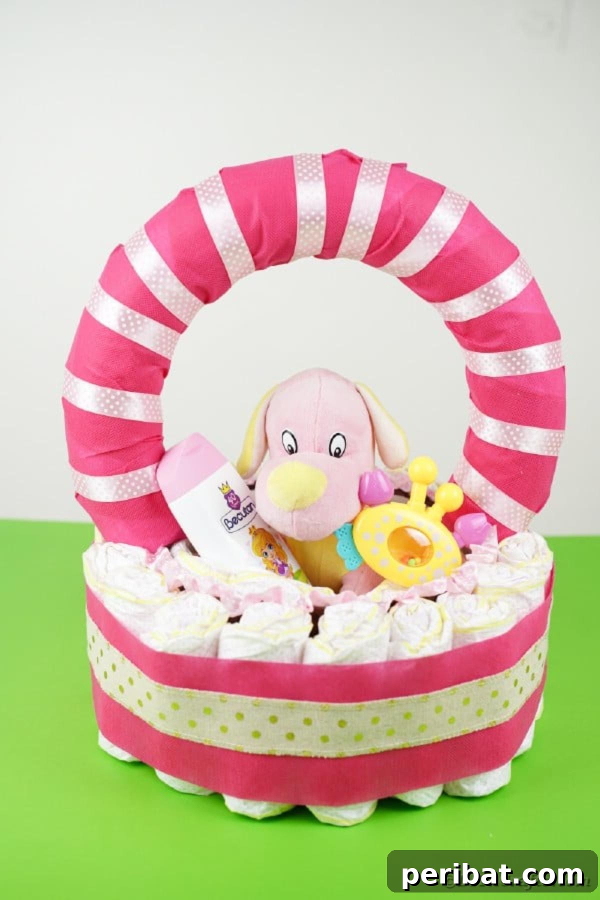 Charming Pink Handmade Diaper Basket Baby Shower Present 26 Completed diaper cake basket with pink ribbons and a gold accent, resting on a vibrant green surface