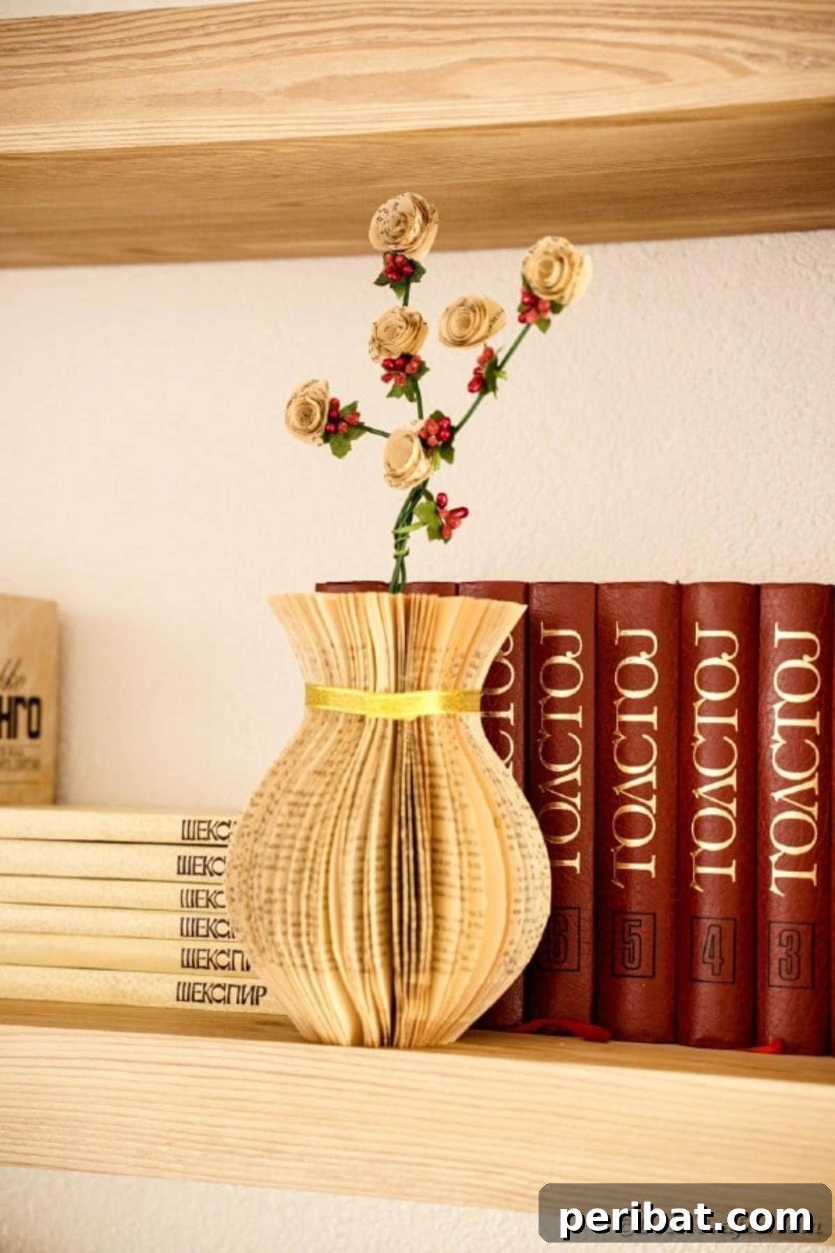 A sophisticated paper vase, carefully constructed from the pages of an old book, displayed on a wooden shelf, adding a touch of vintage literary flair to the room's decor.