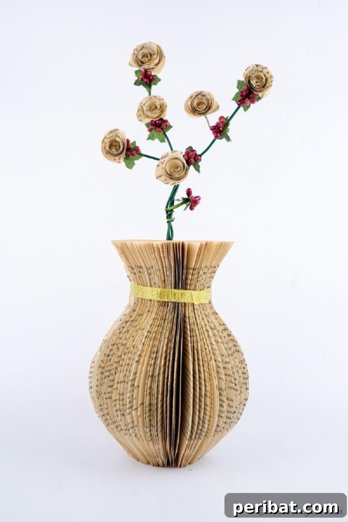 A pristine paper vase crafted from old book pages, meticulously cut and assembled, displayed on a clean white surface, showcasing its elegant form and literary charm.