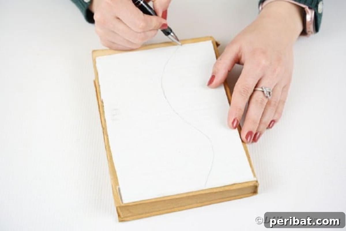 A hand drawing the outline of a vase onto a piece of cardboard, serving as a template for crafting the paper vase.