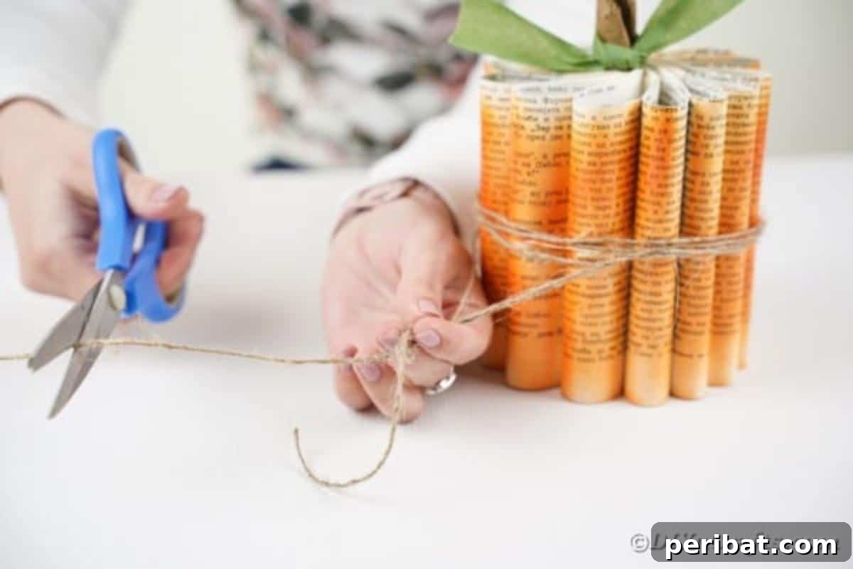 Storybook Pumpkin Charm 22 Twine being wrapped around the middle of the paper pumpkin, enhancing its rustic aesthetic.