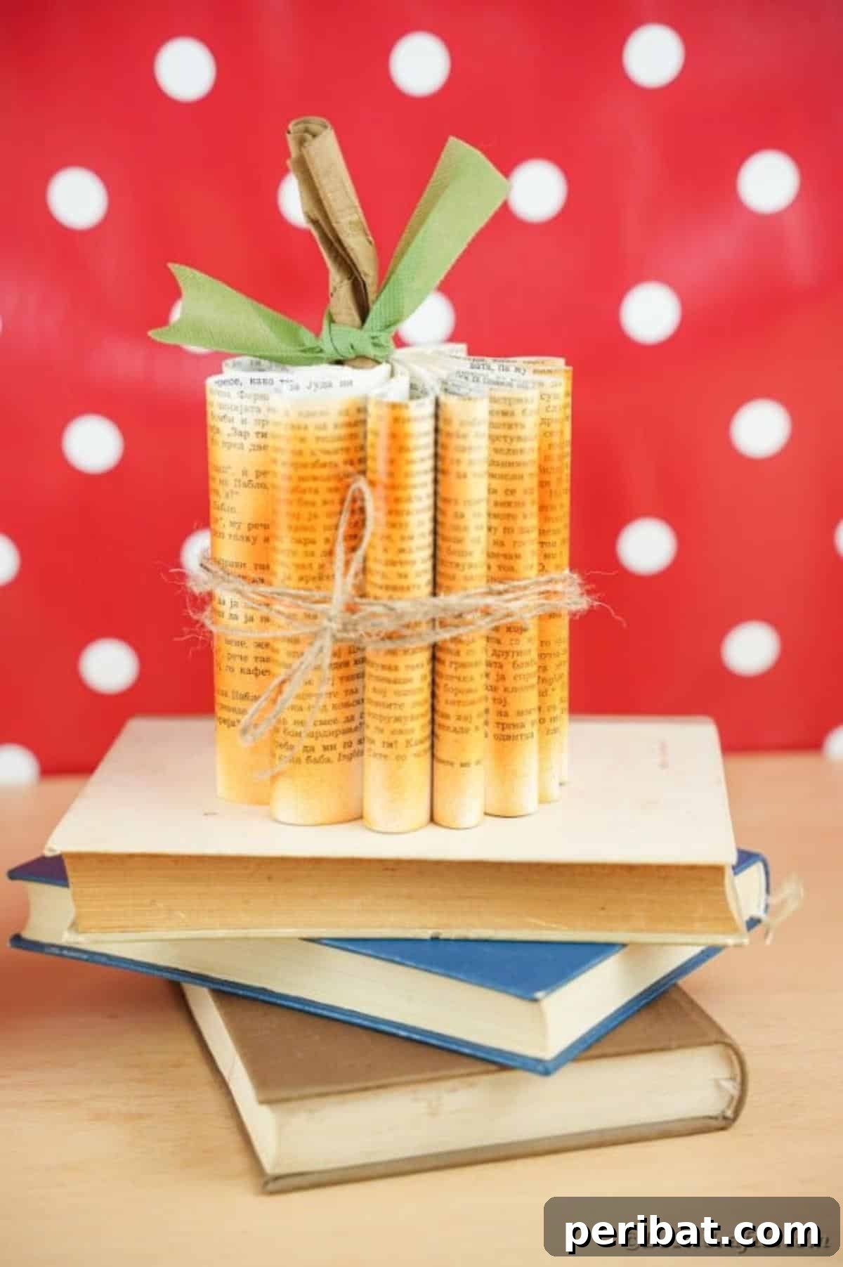 Storybook Pumpkin Charm 34 A book page pumpkin placed on a stack of vintage books, set against a cheerful polka dot background, showcasing its charm.