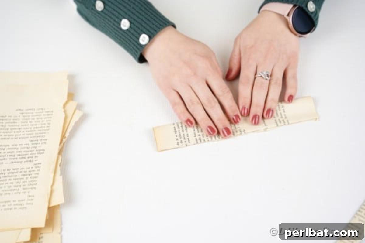 A piece of paper, already folded once, being folded in half again to create a narrower strip.