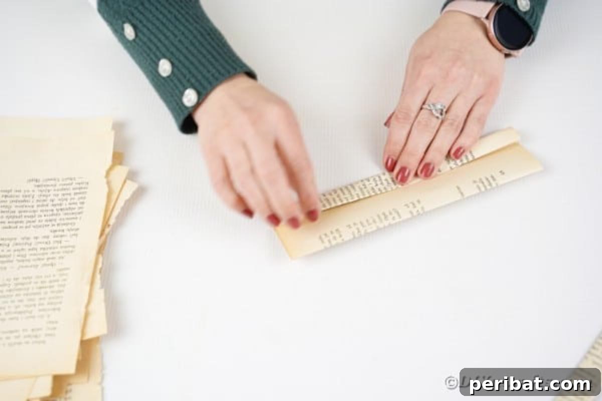 A piece of paper being folded in half lengthwise, creating a precise and narrow strip.