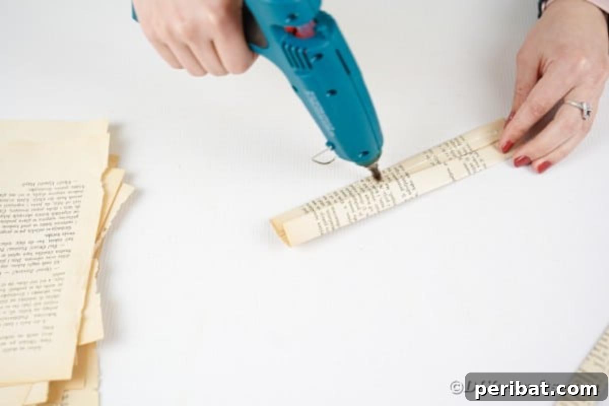 Hot glue is carefully applied to the edges of a folded paper strip, preparing it to be sealed securely.