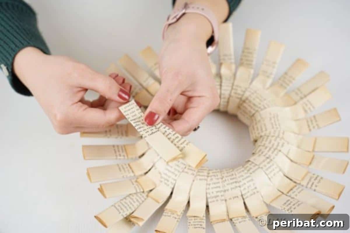 A folded paper strip is being bent at an angle, preparing it to be added as a second, textured layer to the wreath.