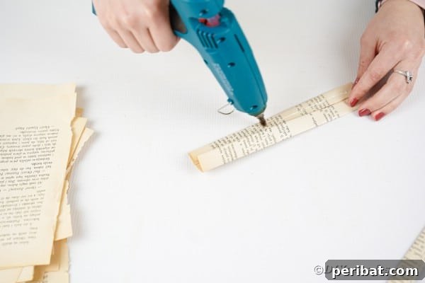 Hot glue is carefully applied to the edges of a folded paper strip, preparing it to be sealed securely.