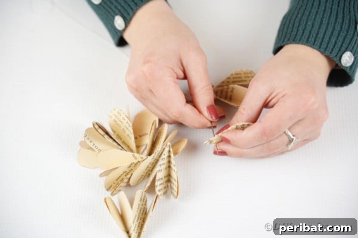 Charming Blooms from Repurposed Book Pages 16 Sewing paper flower together, showing a needle and thread piercing the pointed ends of paper petal bundles