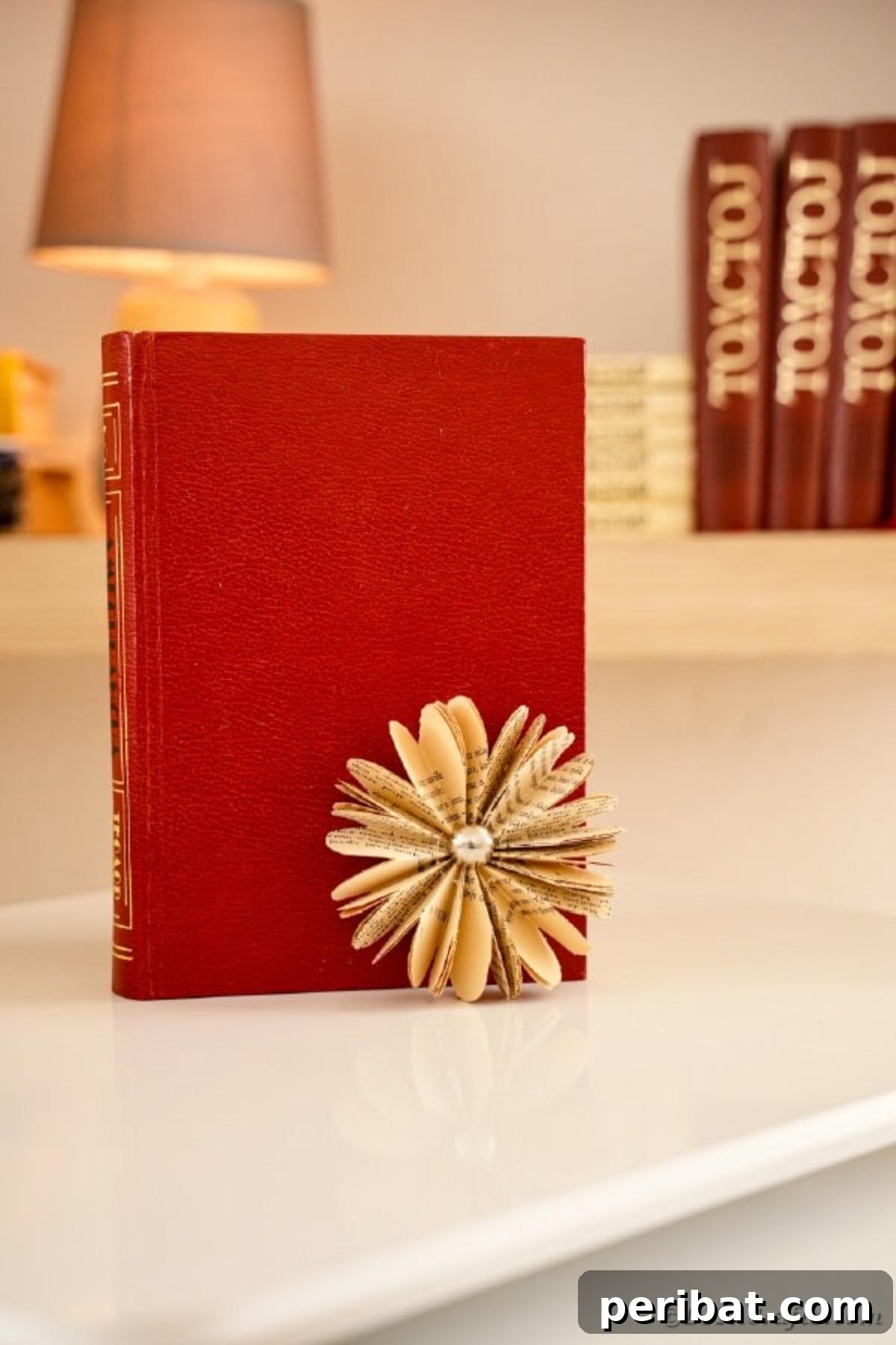 Charming Blooms from Repurposed Book Pages 4 A beautifully crafted old book page flower resting against a vibrant red book, highlighting its vintage charm
