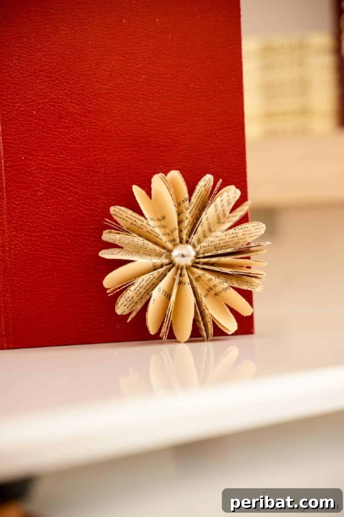 Charming Blooms from Repurposed Book Pages 23 A charming paper flower crafted from old book pages, set against the rich color of a red book