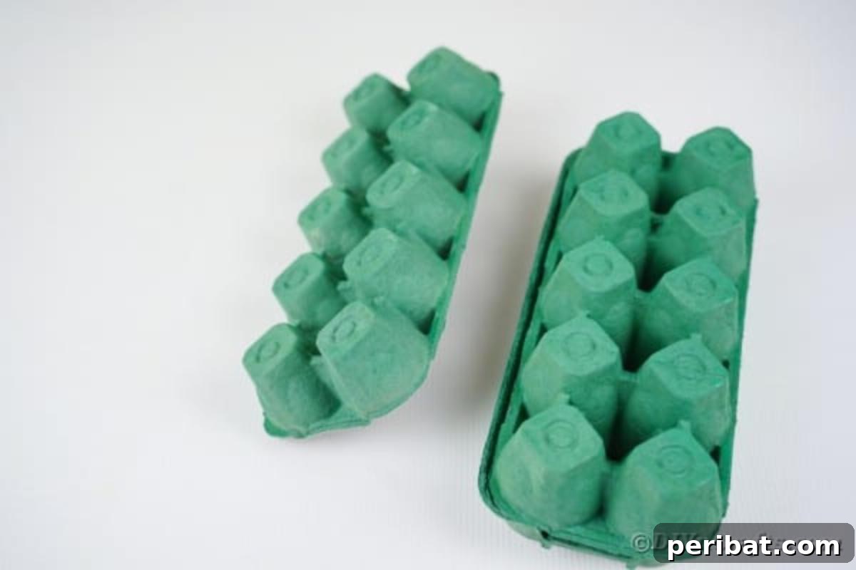 Three painted green egg carton sections drying on a table surface.
