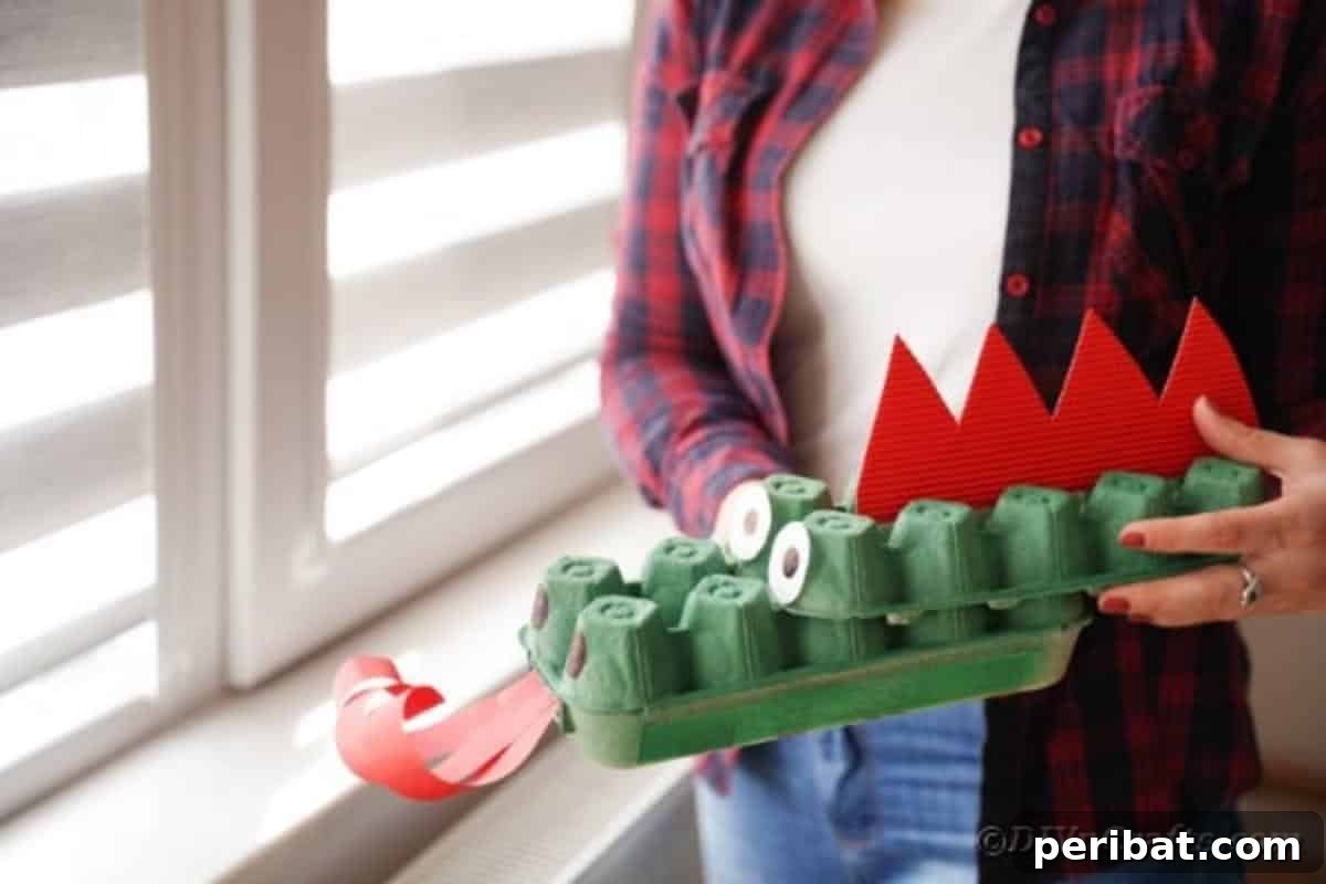 A close-up of a person holding a green egg carton dragon, showcasing its textured body and red spikes.
