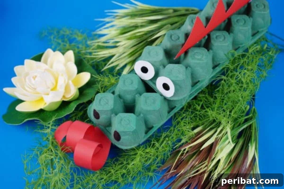 A green egg carton dragon with red details, sitting on a textured blue fabric background.