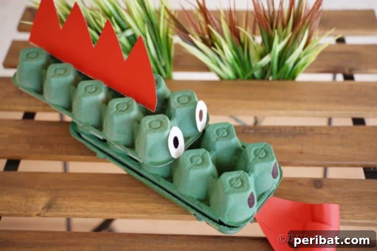 A green egg carton dragon craft sitting on a rustic wooden table.