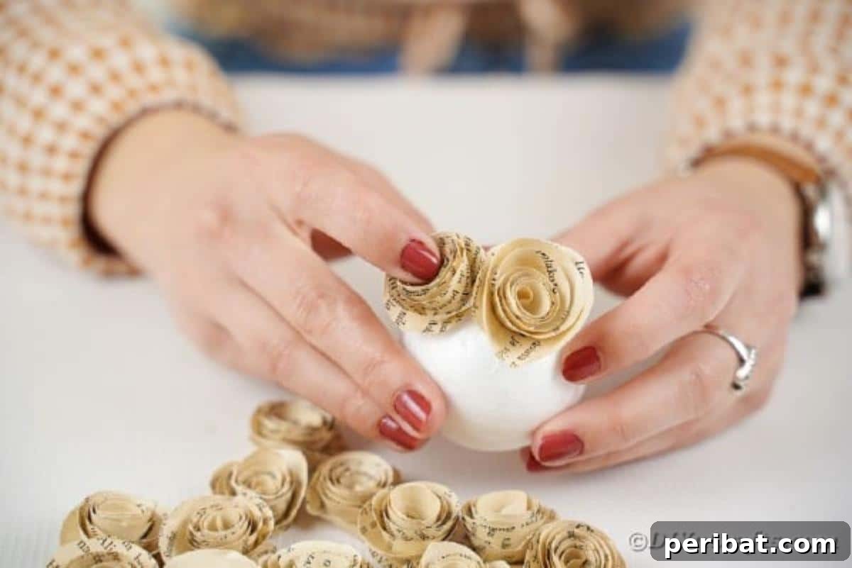 From Pages to Petals: DIY Book Rose Sphere 13 A crafter gluing individual paper roses onto a styrofoam ball, beginning to cover the surface