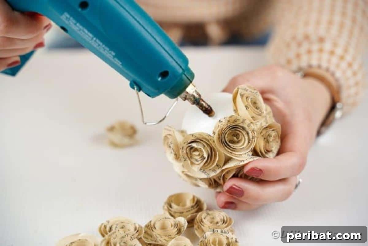 From Pages to Petals: DIY Book Rose Sphere 14 The process of gluing paper roses to a styrofoam ball, showing significant progress in covering the sphere