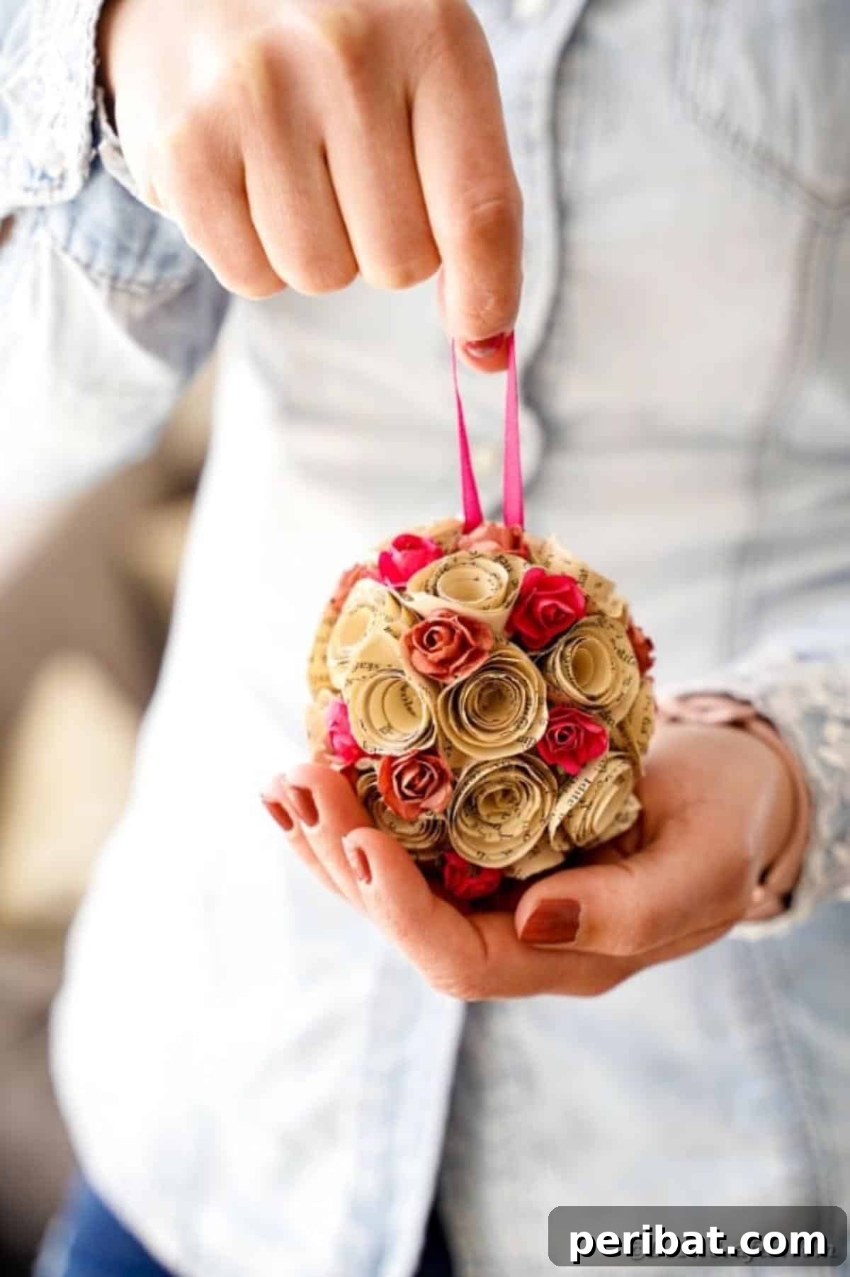 From Pages to Petals: DIY Book Rose Sphere 18 Another view of a woman holding a paper rose ball, highlighting its handcrafted elegance