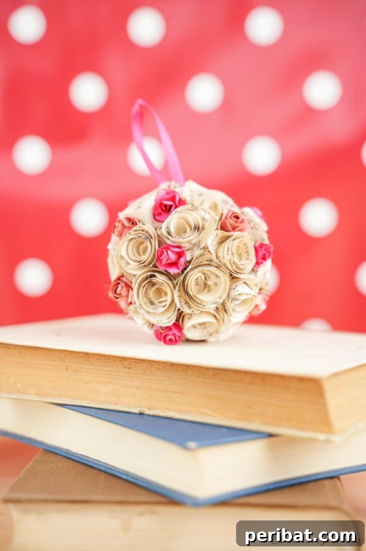 From Pages to Petals: DIY Book Rose Sphere 4 An intricately designed rose paper ball sits atop a stack of vintage books, creating a charming display