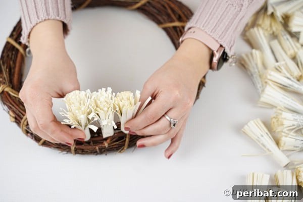 Gluing the first row of fringed paper flowers onto the grapevine wreath form