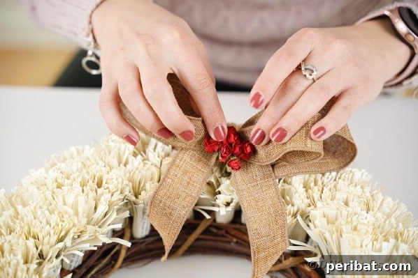 A woman tying a decorative bow onto the completed fringed book page wreath