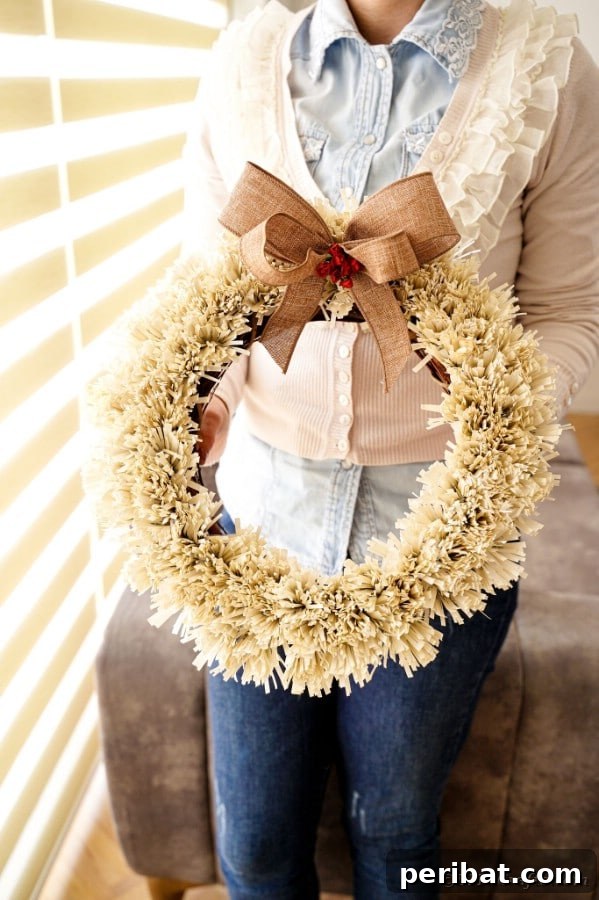 A woman proudly holding her finished paper fringe wreath, ready for display