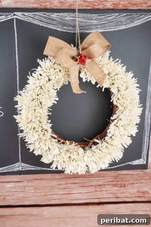 Fringed wreath hanging on a rustic chalkboard, close-up details