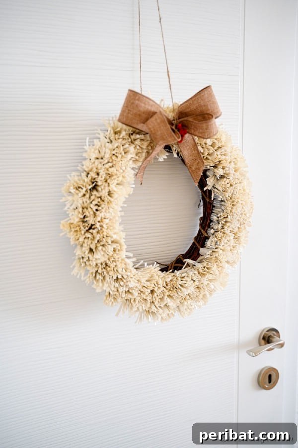 Fringed wreath against a crisp white door, highlighting its simple elegance