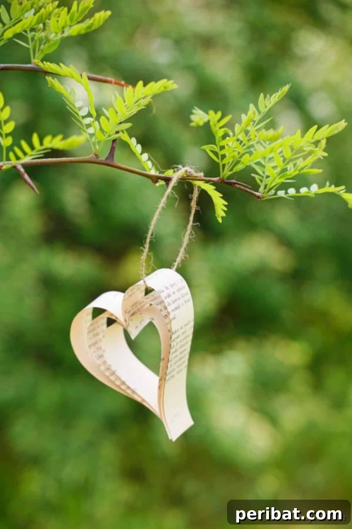 Heirloom Book Page Heart Bunting 21 A single handcrafted paper heart from an old book page hanging from a tree branch