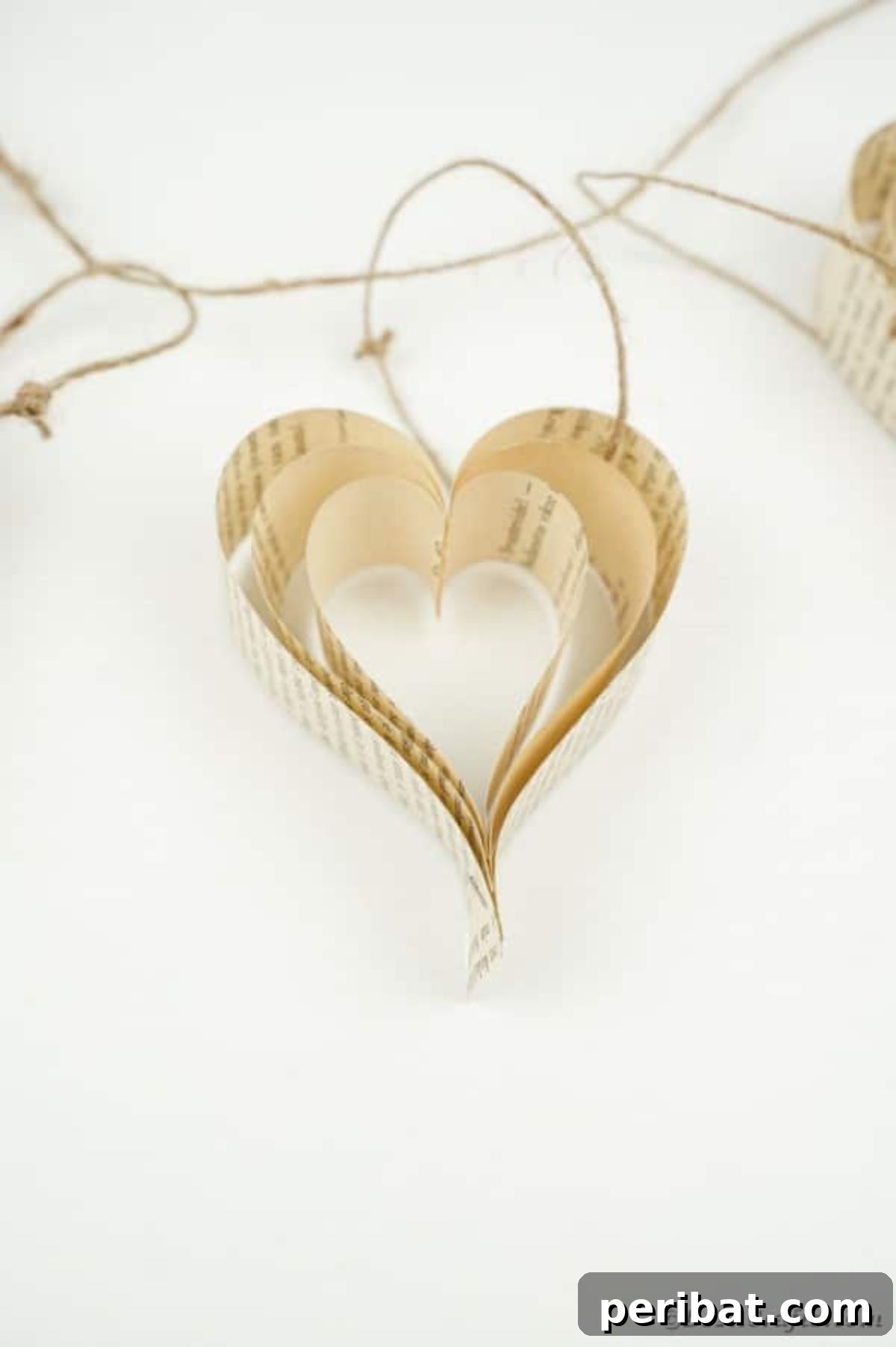 Heirloom Book Page Heart Bunting 22 A delicate paper heart crafted from an old book page resting on a white surface