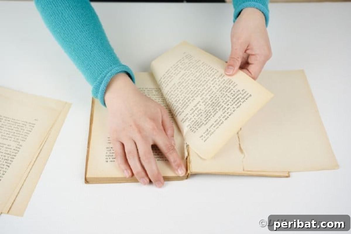 Heirloom Book Page Heart Bunting 7 Hands carefully tearing pages from an old book, preparing for the heart banner craft