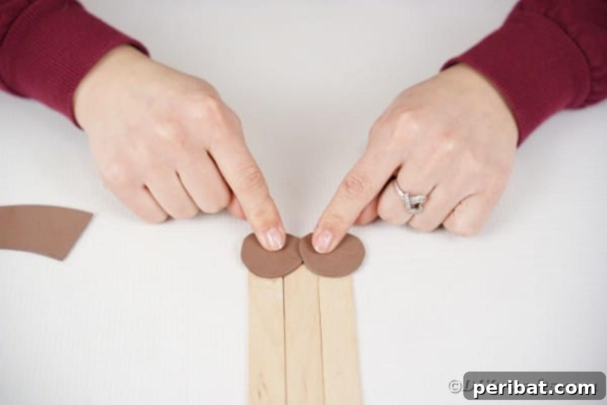 Gluing brown paper paws onto the bottom of the craft stick dog's legs
