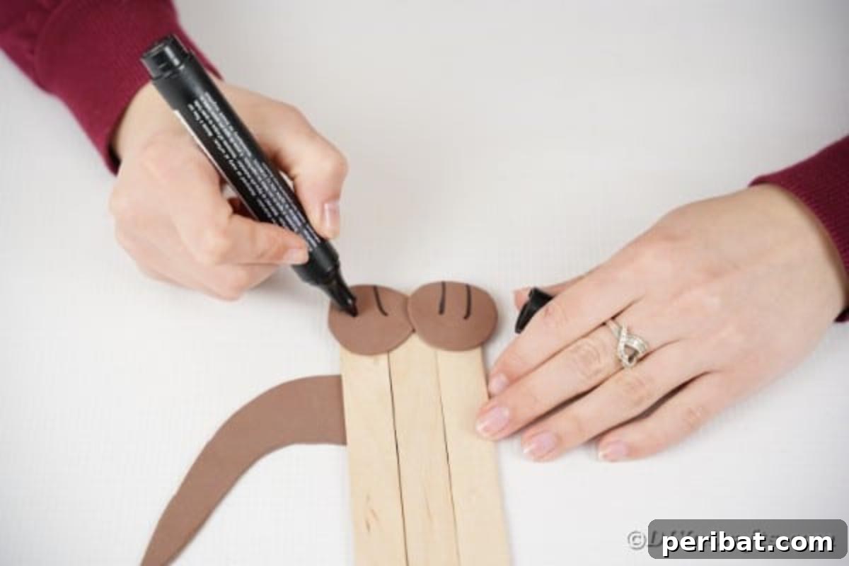 Using a black marker to draw toes on the puppy's paper paws