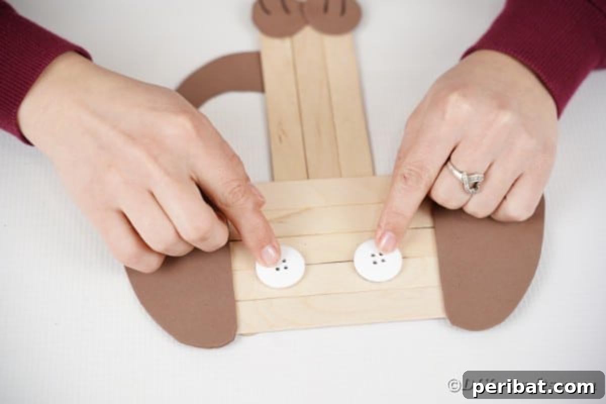Gluing two white paper circles onto the craft stick puppy's head for eyes