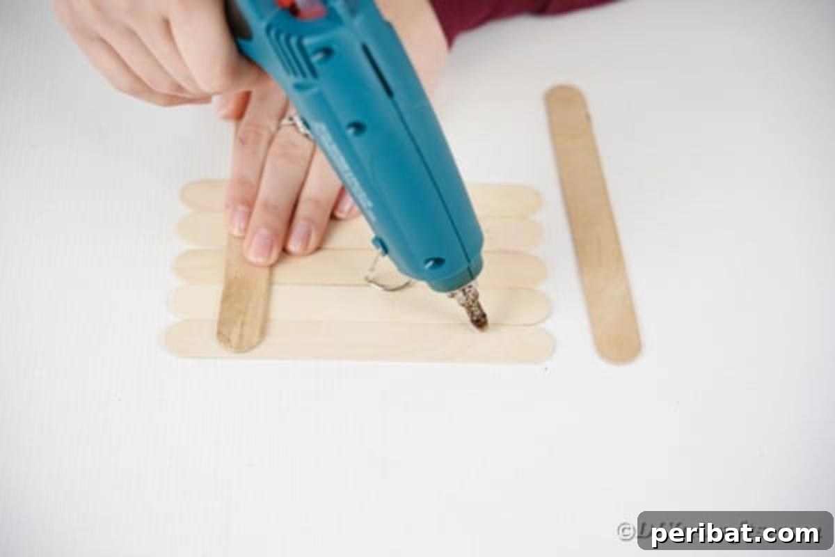 Gluing five craft sticks horizontally, then two vertically to secure them