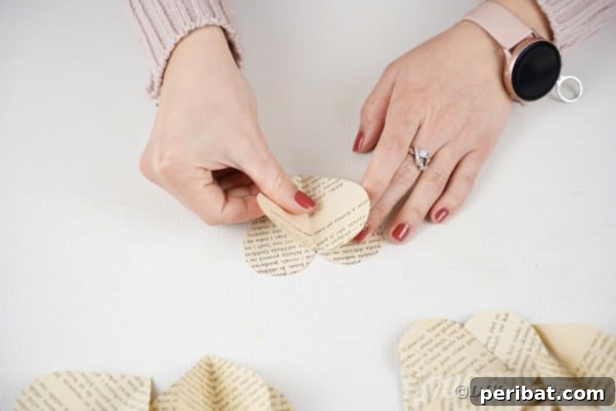 Combining two folded paper hearts by gluing their creases together to create a 3D effect