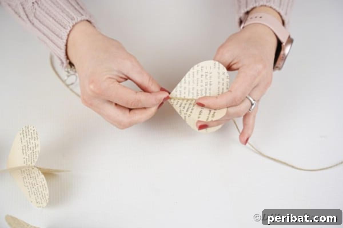 Carefully gluing individual paper hearts onto a length of twine to form a garland strand