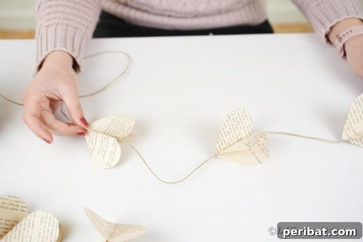 A woman proudly holding a finished DIY paper heart garland, showcasing the assembled strands