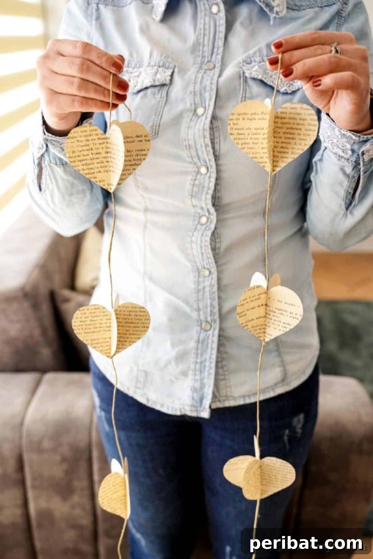 A woman displaying a charming book page heart garland, ready to adorn a mantel or wall
