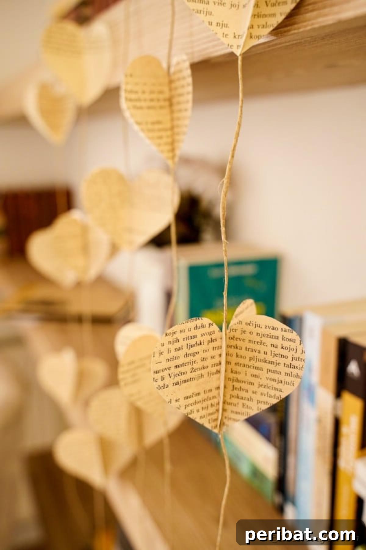 Upcycled book page heart garland hanging gracefully by a rustic wooden bookshelf, enhancing country chic home decor