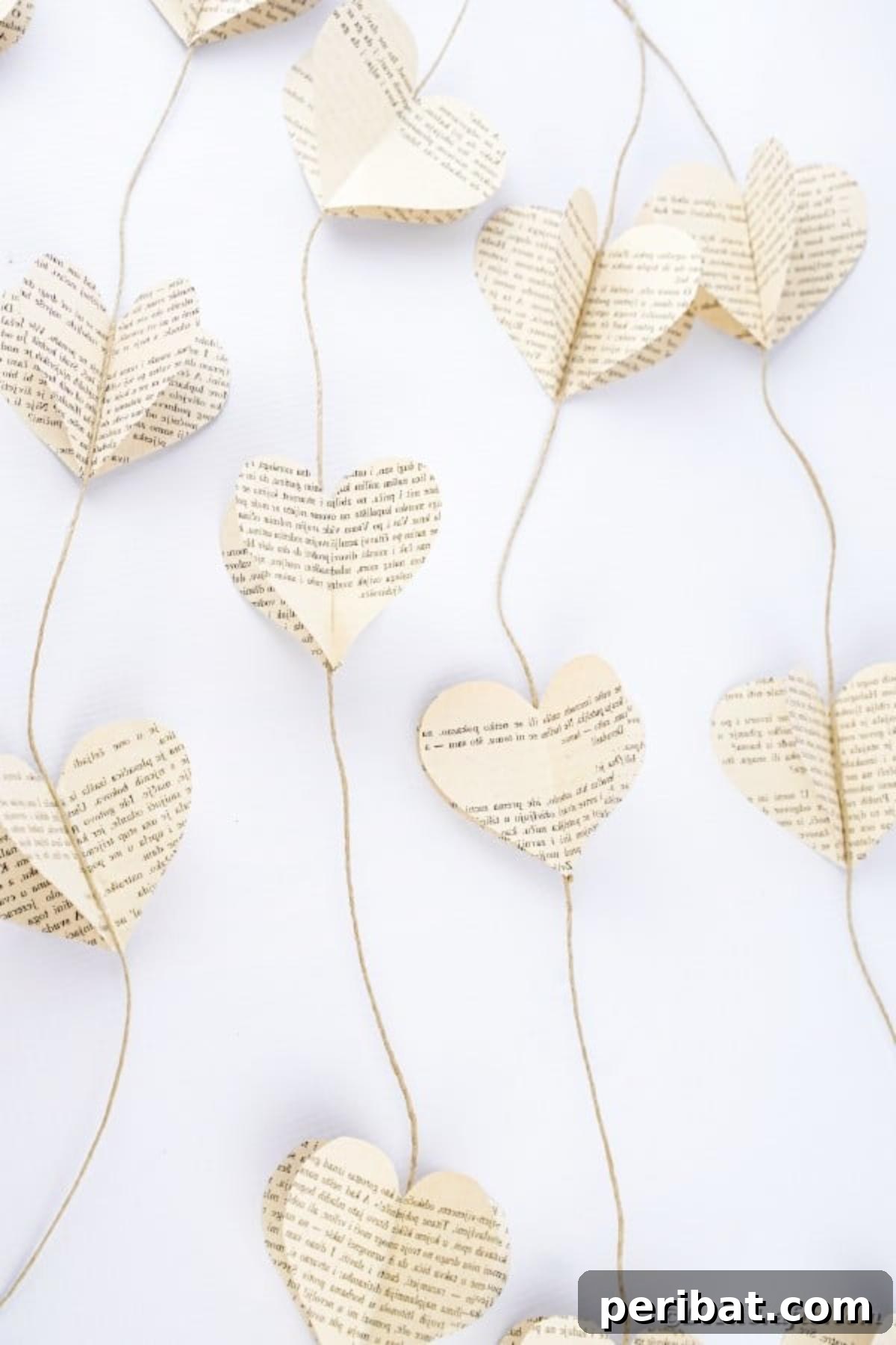 Detailed view of a handmade paper heart garland, showcasing its rustic beauty on a white wooden surface