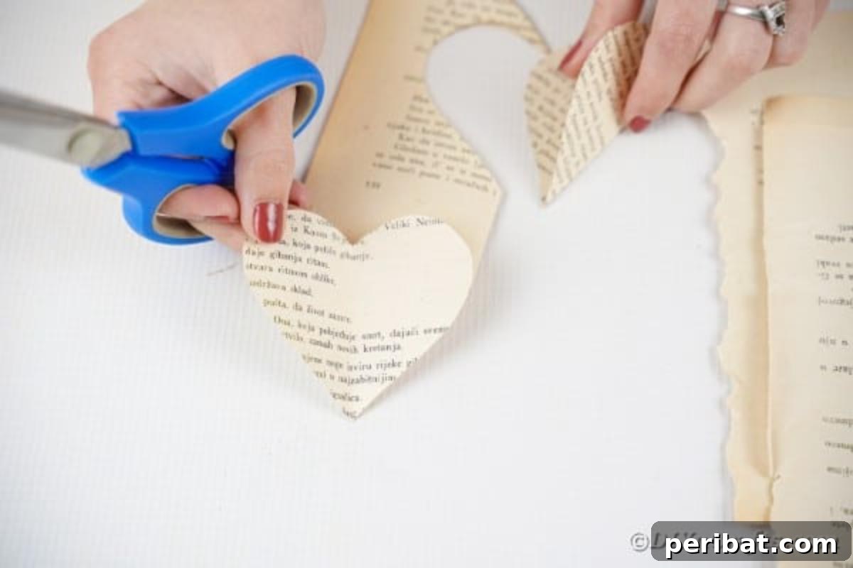 Holding a single heart cut from an old book page, ready for garland assembly