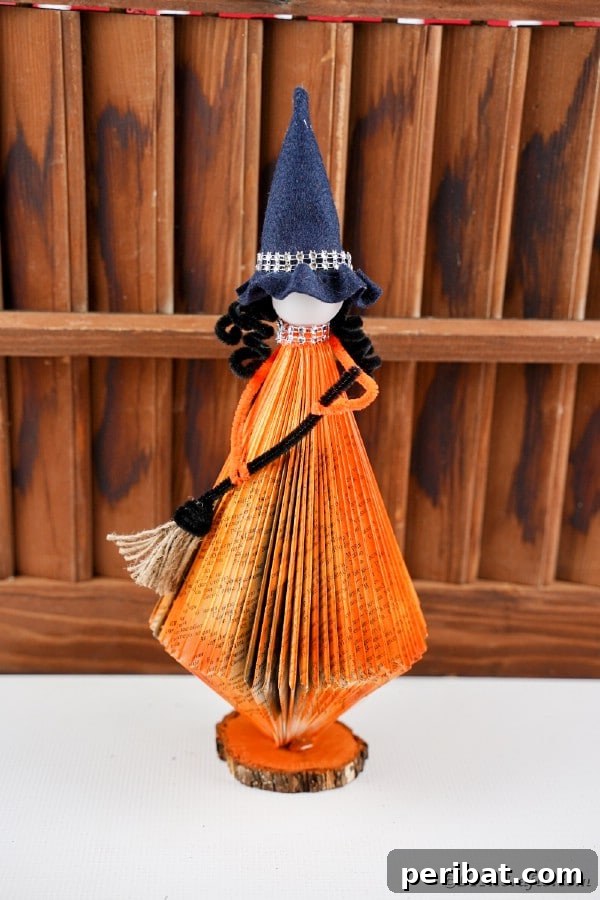 Upcycled Book Floating Witch Halloween Decor 5 Orange witch in front of slats