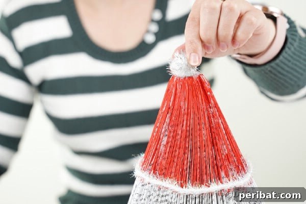 Gluing pom pom to top of santa hat