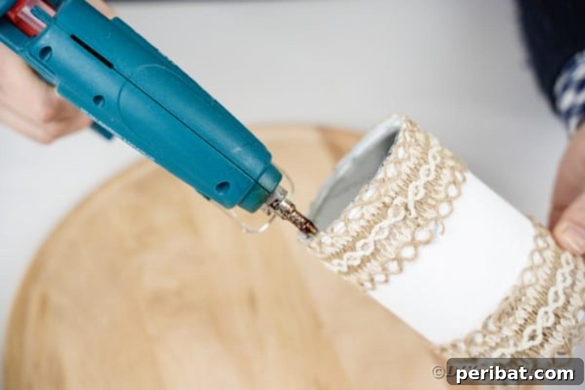 Farmhouse Storage from Repurposed Pringles Cans 14 Applying hot glue to the bottom of a white Pringles can before attaching it to a wooden board
