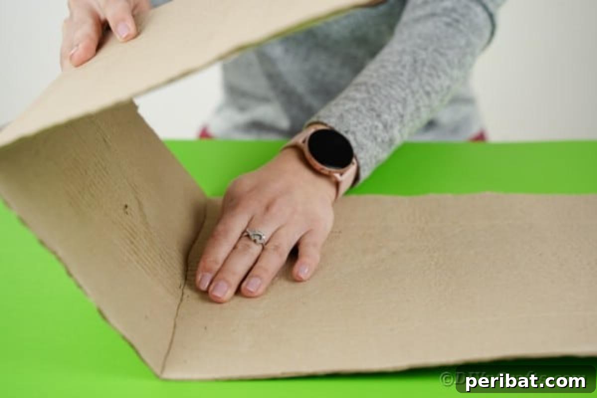 A hand measuring and scoring a large piece of cardboard, preparing it for folding to construct the crane's cab with precise dimensions.