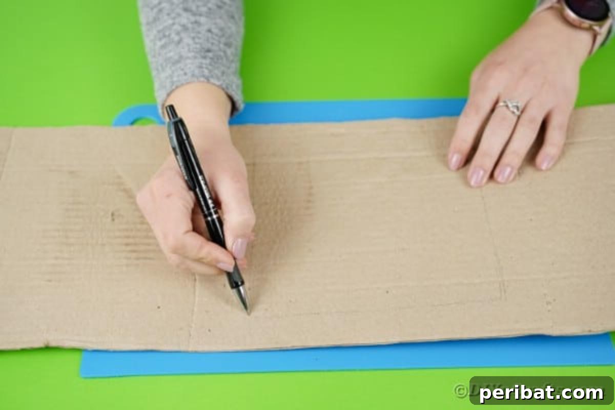 A hand drawing a square onto a folded section of cardboard, outlining the window area for the crane's cab, demonstrating precision in design.